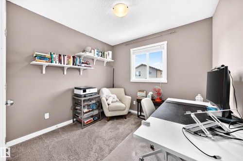 Neutral wall paint, textured carpet, window with white trim, flush mount ceiling light, and built-in wall shelving - 16832 53 Street Nw, Edmonton, AB 