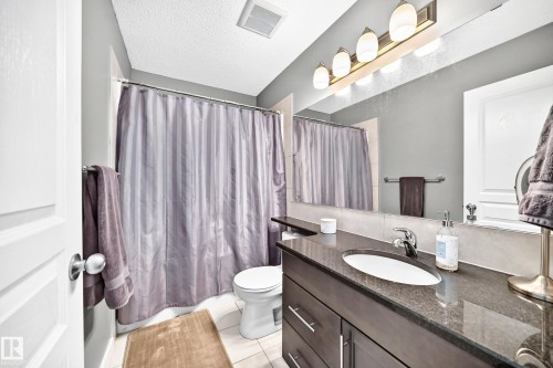 Vanity with a dark stone countertop, undermount sink, and chrome faucet - 16832 53 Street Nw, Edmonton, AB 
