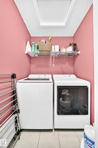 Laundry area featuring tile flooring, a built-in wire shelf, and a skylight - 16832 53 Street Nw, Edmonton, AB 