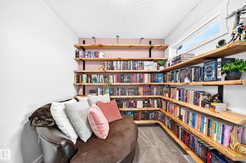 Built-in wood-finish shelving with black metal brackets, painted accent wall, and a long horizontal window - 16832 53 Street Nw, Edmonton, AB 