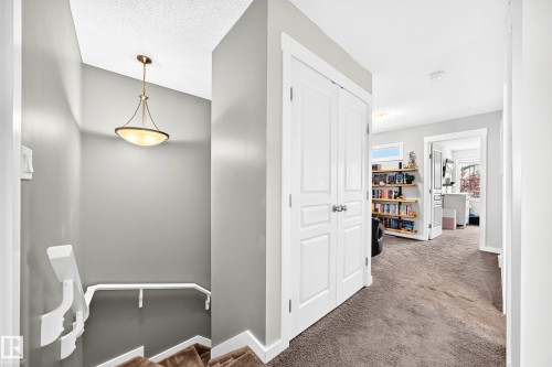 Stairwell featuring a contemporary pendant light fixture and white railing - 16832 53 Street Nw, Edmonton, AB 