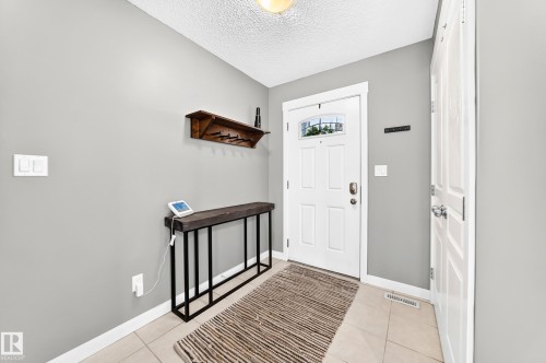 Tiled flooring entryway featuring a white paneled door with windowpane detailing and a white paneled closet door - 16832 53 Street Nw, Edmonton, AB 