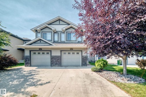 Contemporary multi-level exterior with gabled roof lines, dual attached garage doors, stone veneer accents, and a concrete driveway - 16832 53 Street Nw, Edmonton, AB 
