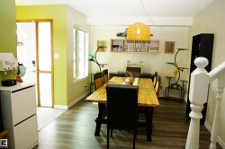 Wood-finish flooring throughout, paired with a large window, a built-in wall shelf, and a staircase with white balusters - 
