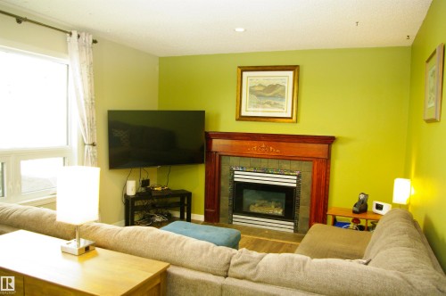 Fireplace with wood-finish mantel and tile surround, recessed lighting, and wood-finish flooring - 25 Hasen Close, St. Albert, AB 