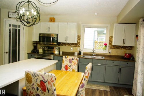 Modern kitchen featuring two-tone cabinetry, stainless steel appliances, and a mosaic tile backsplash - 25 Hasen Close, St. Albert, AB 