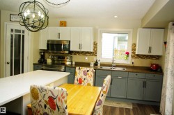 Modern kitchen featuring two-tone cabinetry, stainless steel appliances, and a mosaic tile backsplash - 