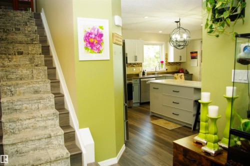 Wood-finish flooring, white cabinetry, light-toned countertops, and a decorative pendant light fixture - 25 Hasen Close, St. Albert, AB 
