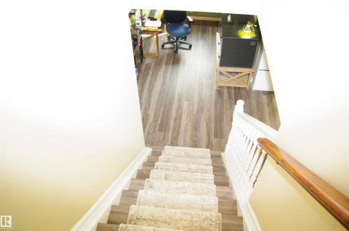 Staircase featuring a carpet runner, white balusters, and a wood handrail - 25 Hasen Close, St. Albert, AB 