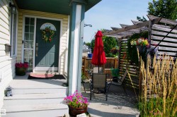 Siding exterior with a covered porch featuring a solid front door with an arched transom window - 