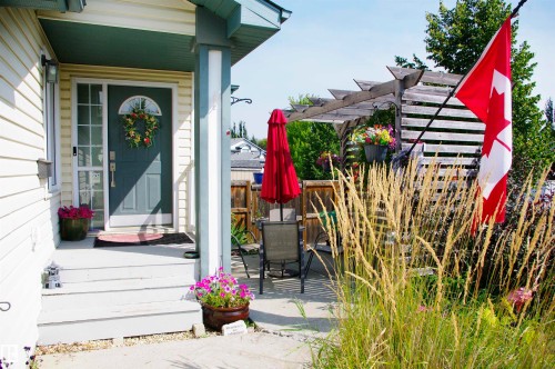 Front entrance with a dark-paneled door and a storm door - 25 Hasen Close, St. Albert, AB 