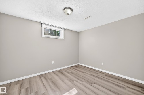 Wood-finish flooring, light gray wall paint, white trim, and a window with white casing - 3 Grantham Place, St. Albert, AB 