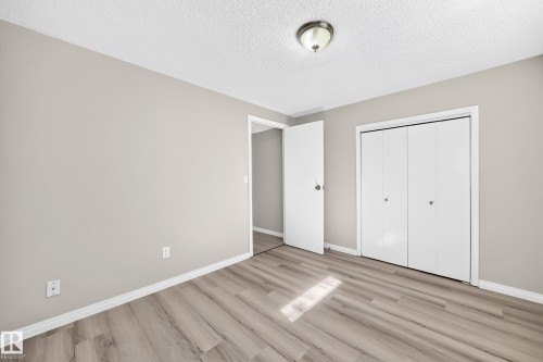 Light gray painted walls, wood-finish flooring, white bi-fold closet doors, white door, and a flush mount ceiling light - 3 Grantham Place, St. Albert, AB 