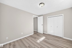 Light gray painted walls, wood-finish flooring, white bi-fold closet doors, white door, and a flush mount ceiling light - 