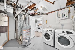 Laundry area featuring a side-by-side washer and dryer, water heater, and exposed overhead utilities - 