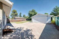 Detached garage with siding exterior, wide concrete driveway, and a wood privacy fence - 