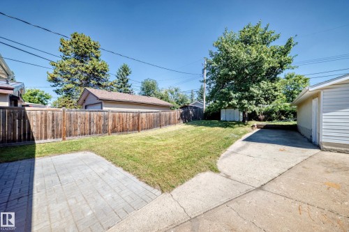 Expansive yard featuring a manicured lawn, wood privacy fencing, concrete driveway, and a paved patio area - 3 Grantham Place, St. Albert, AB 