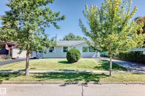 Single-story property featuring light-colored siding, a front lawn with mature trees, and a paved driveway - 3 Grantham Place, St. Albert, AB 