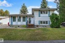 White siding exterior with blue decorative shutters, a wooden entry staircase, and a manicured front lawn - 16016 78A Avenue Nw, Edmonton, AB 