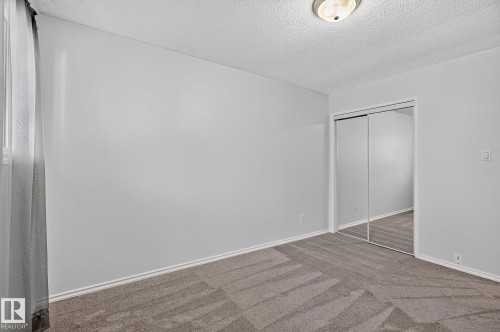 Wall-to-wall carpeting with a geometric pattern, mirrored closet doors, and flush-mount ceiling lighting - 16016 78A Avenue Nw, Edmonton, AB 
