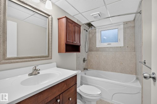 Vanity with integrated sink, wood-finish cabinetry, and brushed nickel faucet - 16016 78A Avenue Nw, Edmonton, AB 