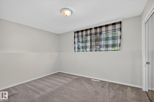 Recessed window with black and white plaid curtains, neutral painted walls, and gray carpet flooring - 16016 78A Avenue Nw, Edmonton, AB 