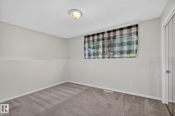 Recessed window with black and white plaid curtains, neutral painted walls, and gray carpet flooring - 