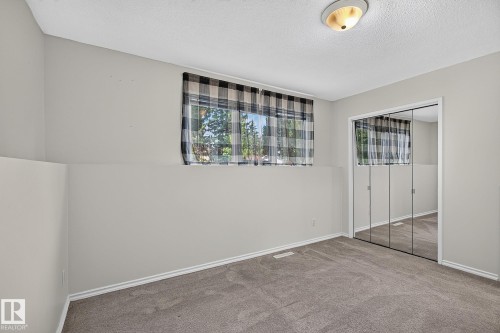 Neutral wall paint, ceiling light fixture, grey carpeting, and mirrored bi-fold closet doors - 16016 78A Avenue Nw, Edmonton, AB 