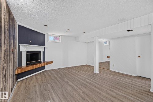 Spacious room featuring wood-finish flooring, a built-in fireplace with a mantel, and recessed lighting - 16016 78A Avenue Nw, Edmonton, AB 
