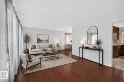 Expansive living space featuring wood-finish flooring, abundant natural light from large windows, and a neutral color palette - 