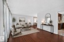 Expansive living space featuring wood-finish flooring, abundant natural light from large windows, and a neutral color palette - 16016 78A Avenue Nw, Edmonton, AB 