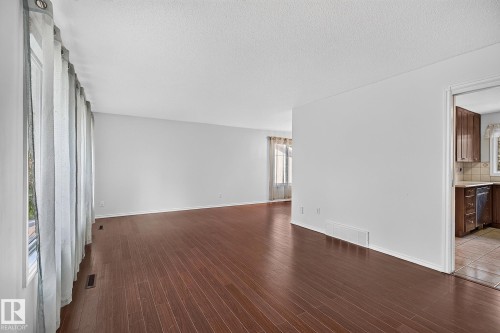 Spacious interior with dark wood-finish flooring, white walls, and a large window - 16016 78A Avenue Nw, Edmonton, AB 