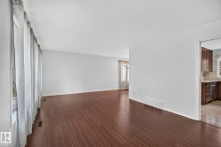 Spacious interior with dark wood-finish flooring, white walls, and a large window - 