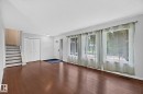 Wood-finish flooring, multiple large windows, and a classic white panel front door with a decorative glass insert - 16016 78A Avenue Nw, Edmonton, AB 