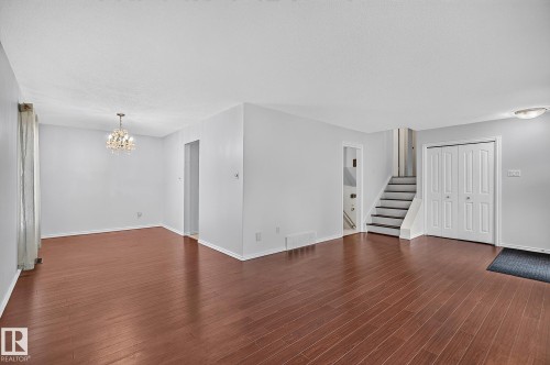 Spacious room featuring wood-finish flooring, a crystal chandelier, and neutral wall tones - 16016 78A Avenue Nw, Edmonton, AB 