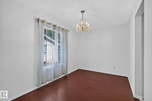 Warm wood-finish flooring complemented by a crystal chandelier and neutral wall tones - 16016 78A Avenue Nw, Edmonton, AB 