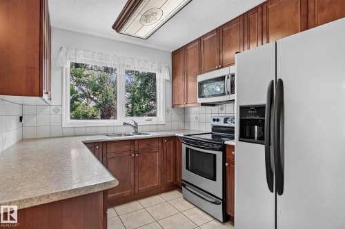 Wood-finish cabinetry paired with light-toned countertops - 16016 78A Avenue Nw, Edmonton, AB 