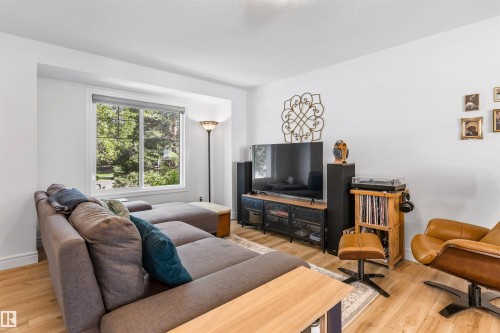 Recessed window with a roller shade, wood-finish flooring, and white walls - #71 330 Bulyea Rd Nw, Edmonton, AB 