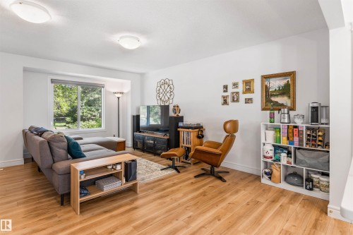 Living area featuring wood-finish flooring, recessed window, and white built-in shelving - #71 330 Bulyea Rd Nw, Edmonton, AB 