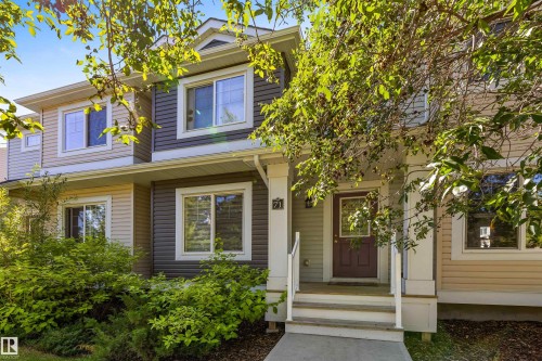 Two-story exterior with multi-toned siding, white trim windows, covered porch, and mature front landscaping - #71 330 Bulyea Rd Nw, Edmonton, AB 