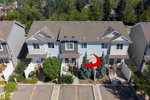 Light blue siding exterior with dark grey accents, pitched shingle roof, paved parking lot, and mature landscaping - #71 330 Bulyea Rd Nw, Edmonton, AB 