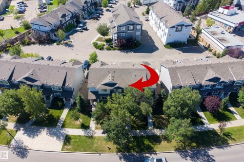 Townhome with a gray pitched roof, mature trees, green lawn, and concrete walkways - #71 330 Bulyea Rd Nw, Edmonton, AB 
