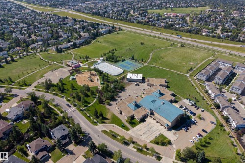 Aerial perspective showcasing a developed neighborhood with mature trees, expansive green spaces, and community amenities - #71 330 Bulyea Rd Nw, Edmonton, AB 