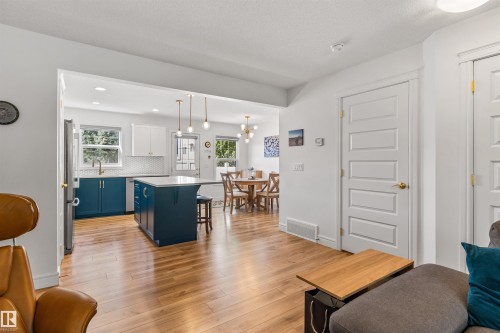 Wood-finish flooring, white paneled doors, and an open concept kitchen with a central island and pendant lighting - #71 330 Bulyea Rd Nw, Edmonton, AB 