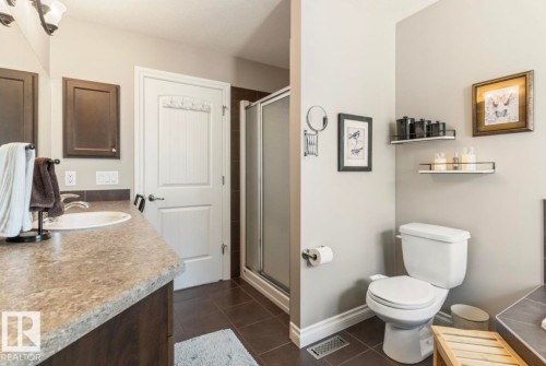 Vanity with a single basin sink and dark wood-finish cabinetry, complemented by a standing shower with a glass enclosure - 22 Voleta Crest, Spruce Grove, AB 