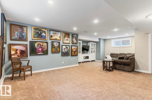 Recessed lighting, light-toned carpeting, a built-in media console with glass-front cabinetry, and a window providing natural light - 22 Voleta Crest, Spruce Grove, AB 