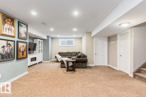 Recessed lighting illuminates the carpeted living area with a built-in media console and a window - 22 Voleta Crest, Spruce Grove, AB 