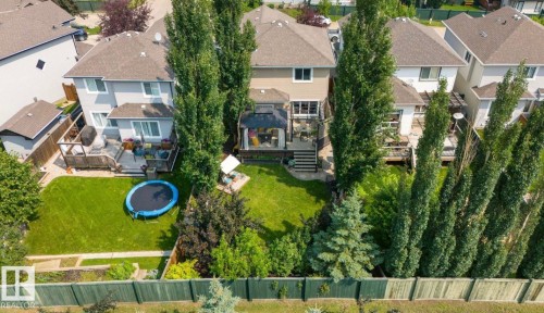 Spacious backyard featuring a manicured lawn, multi-level wood deck, and established perimeter trees - 22 Voleta Crest, Spruce Grove, AB 