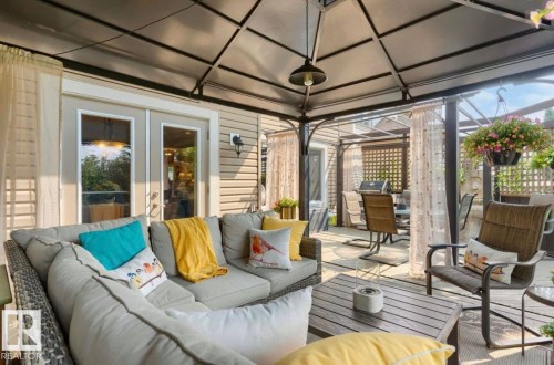 Covered patio featuring a metal gazebo structure, outdoor pendant light, privacy curtains, and wall-mounted exterior lighting - 22 Voleta Crest, Spruce Grove, AB 