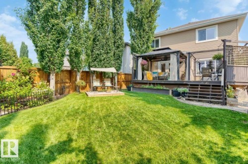 Expansive backyard featuring a lush lawn, a multi-level deck with a gazebo, and a privacy fence - 22 Voleta Crest, Spruce Grove, AB 